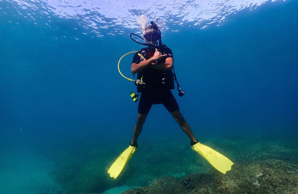 A diver hovering with arms crossed and yellow fins spread